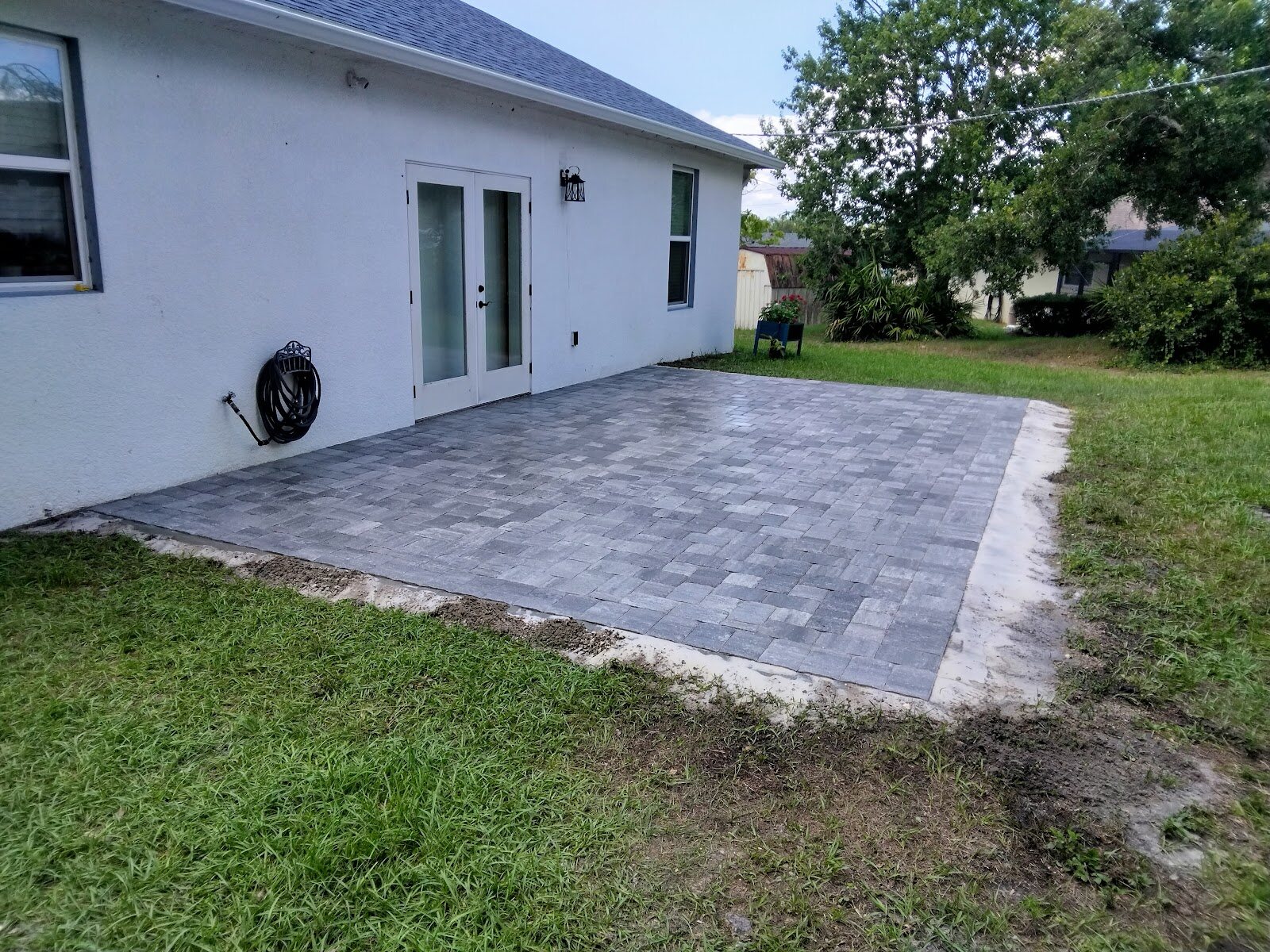 Finished gray paver back patio against a white home, Expert Stone & Brick Pavers
