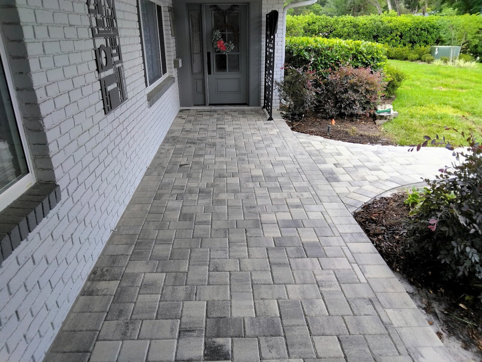 Gray paver walkway leading to a front entry against a white brick home, an Expert Stone & Brick Pavers project